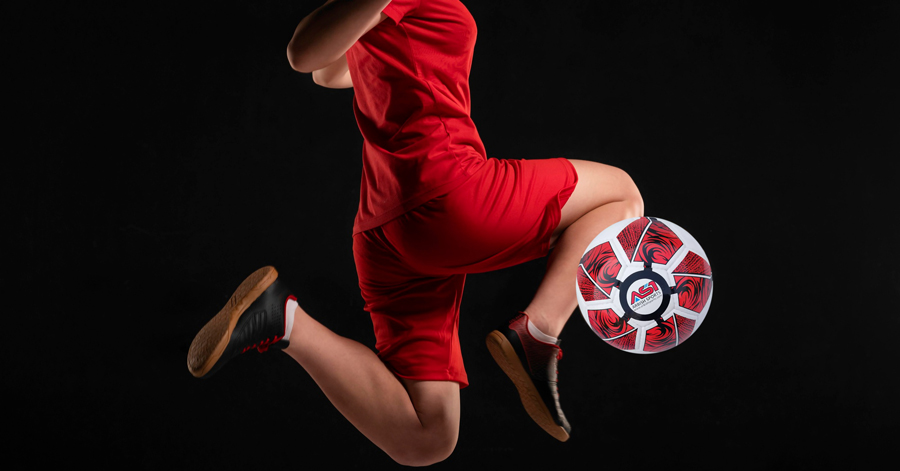 red-soccer-kit-close-up-woman-kicking-ball-with-knee
